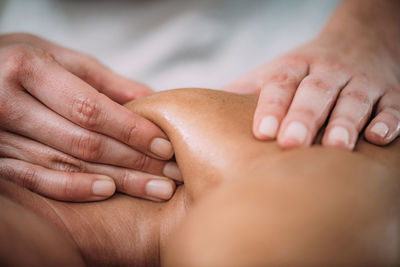 Cropped hands of massage therapist massaging female customer in spa