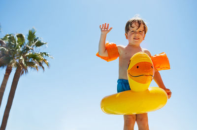 Low angle view of cute girl playing with toys against clear sky