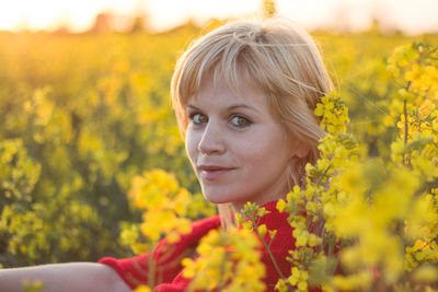 Close-up portrait of young woman with yellow flowers in field