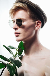 Portrait of young man wearing sunglasses against white background