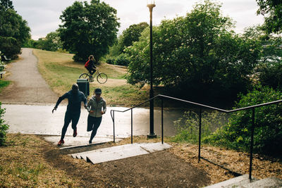 Male and female athletes running towards steps on hill