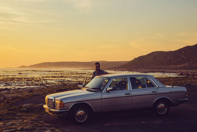Side view of car on road against sky during sunset