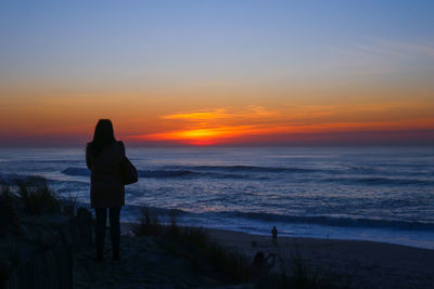 Silhouette people looking at sea against sky during sunset