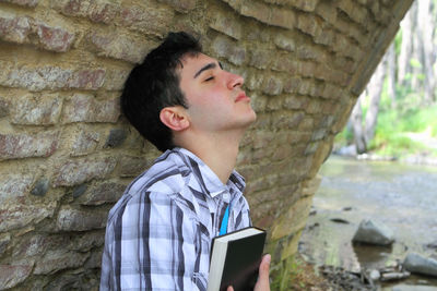 Portrait of boy looking at stone wall