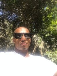 Portrait of smiling man wearing sunglasses against trees