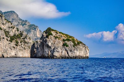 Scenic view of sea and rocks against blue sky