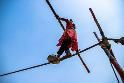 Low angle view of men on rope against clear sky