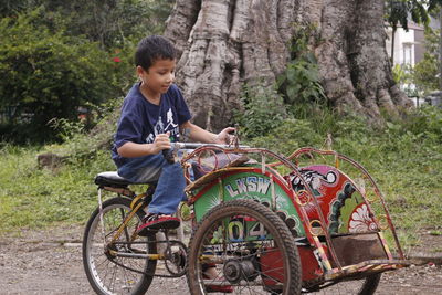 Boy riding pedicab on field