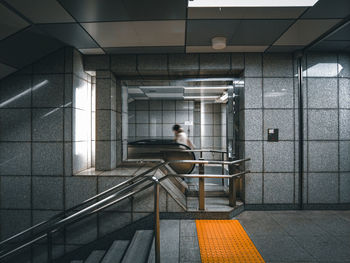 Interior of building, and a person about to ride escalator