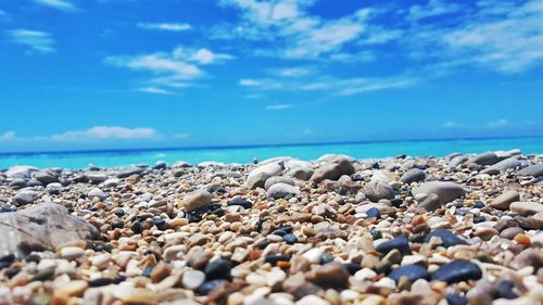 Surface level of pebble beach against blue sky