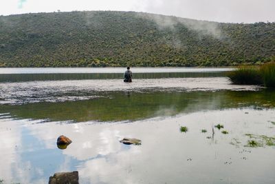 Rear view of a man fishing at lake alice in mount kenya national park, kenya