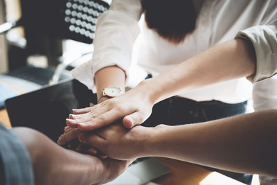 Cropped image of friends stacking hands