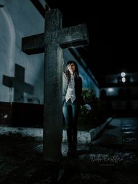 Woman standing on cross at night