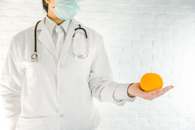 A doctor is showing orange in the lab, eating natural vitamin c nutrition , healthy concept