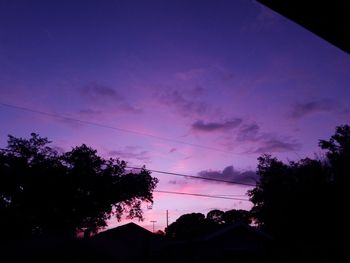 Silhouette trees and buildings against sky at sunset