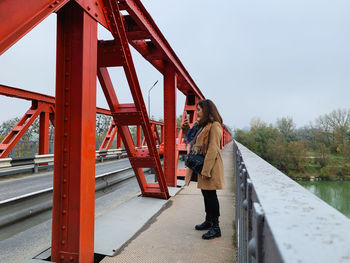 Rear view of woman standing on bridge against sky