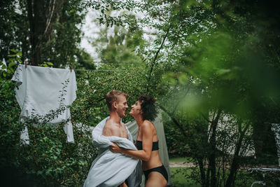 Young couple kissing on plants against trees