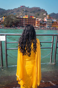 Rear view of woman standing against river