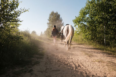 People riding horse on dirt road