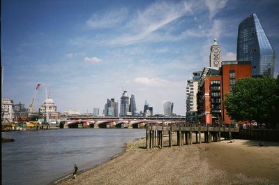 City by river and buildings against sky