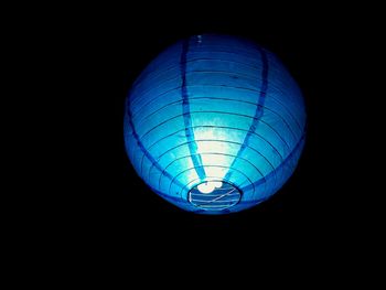 Low angle view of illuminated lighting equipment against black background
