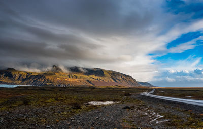 Scenic view of road by mountains against sky