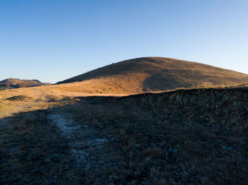 Scenic view of arid landscape against clear blue sky