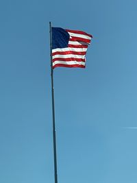 Low angle view of flag against clear blue sky