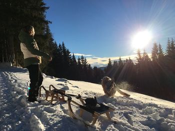 Full length of woman with dog on snow covered field against sky