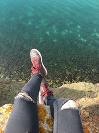 Low section of man sitting by water