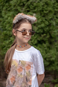 Portrait of young woman wearing sunglasses while standing outdoors