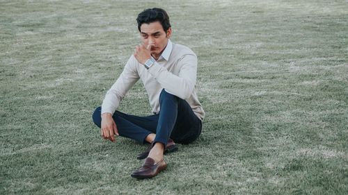Young man sitting on field