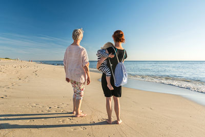 Rear view of people at beach against sky