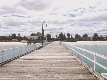 Pier on sea against cloudy sky