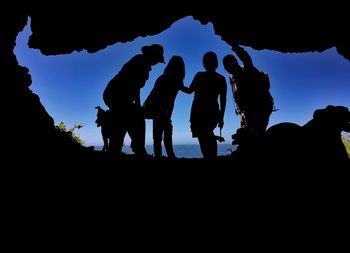 Low angle view of silhouette people on mountain against sky