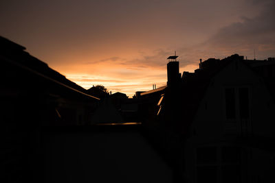 Low angle view of silhouette houses against sky during sunset