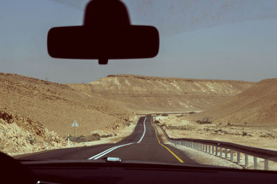 Road leading towards mountain seen through car windshield