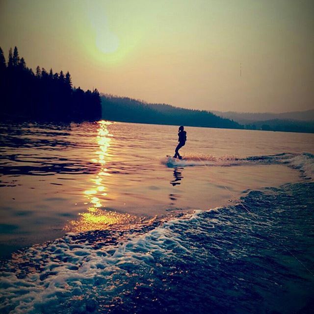 water, sunset, leisure activity, silhouette, lifestyles, reflection, full length, sun, beauty in nature, tranquil scene, tranquility, sea, scenics, nature, waterfront, rippled, lake, sky