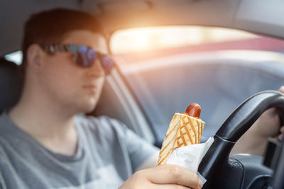 Man holding food while driving car