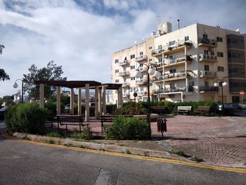 Road by buildings against sky in city