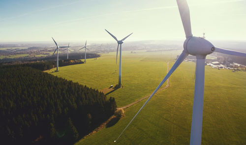 Wind turbines on field against sky