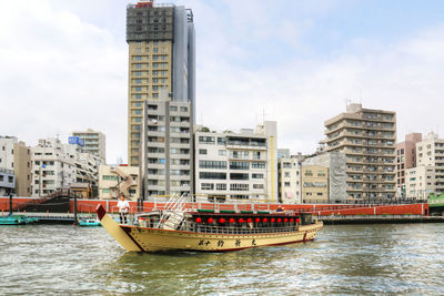 Boat moored in city against sky