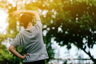 Midsection of woman standing by tree in park