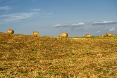 Hay bales on field against sky