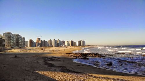 Sea and buildings against clear sky