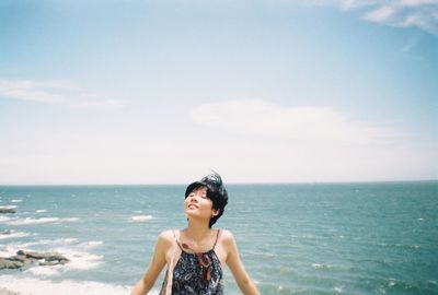 Young woman looking up against sea