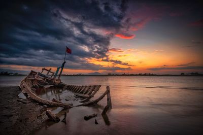 Fishing boat on sea against sky during sunset