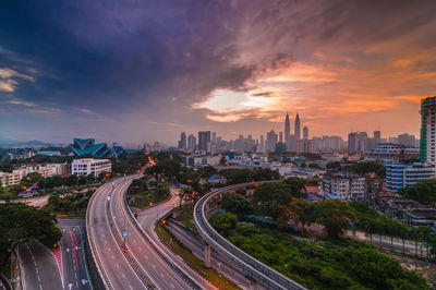 Distant view of petronas towers against sky during sunset in city