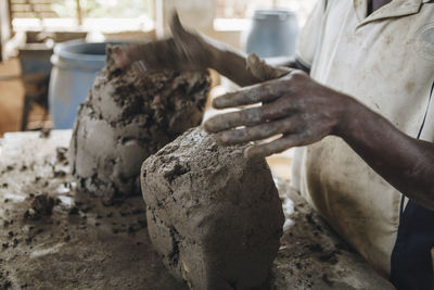 Midsection of worker kneading clay at table in workshop