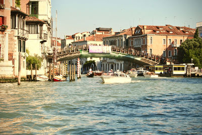 Boats in sea by buildings against clear sky